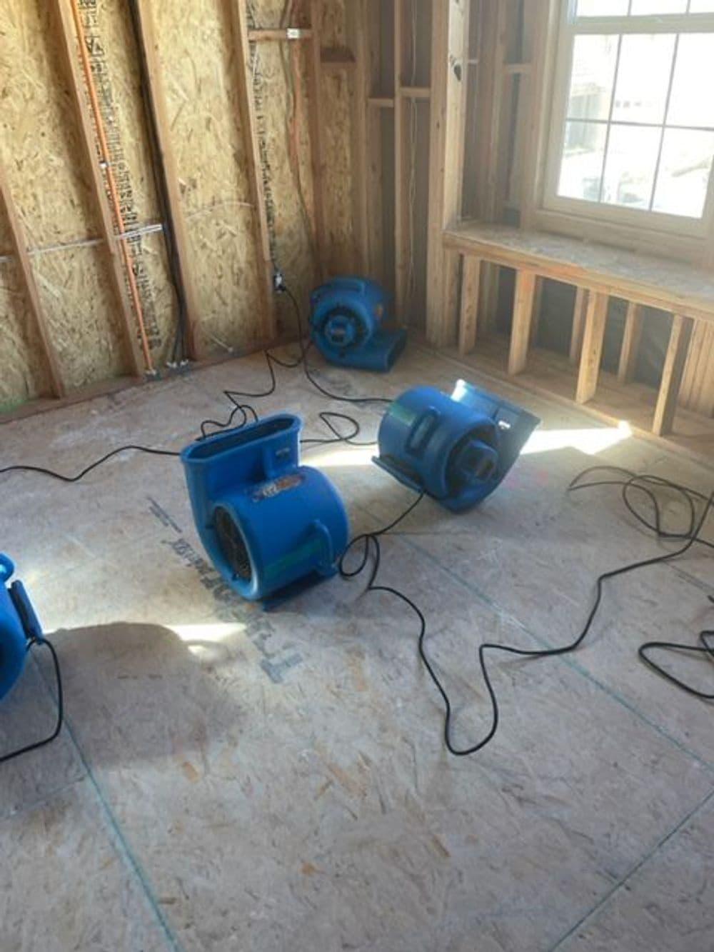 Blue air movers set up in a wooden interior, drying the floor after water damage.