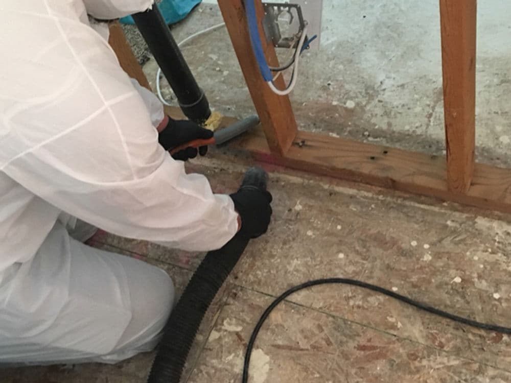 Technician removing debris from floor during restoration work in a damaged building.