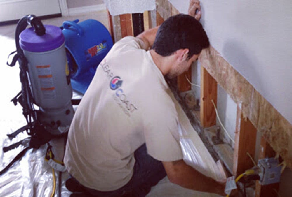 Worker repairing wall insulation with equipment in a home renovation project.