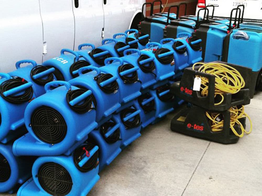 Blue air movers and dehumidifiers stacked for water damage restoration equipment rental.
