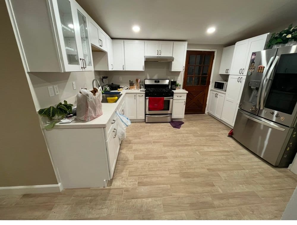 Modern kitchen with white cabinets, stainless steel appliances, and tiled flooring.