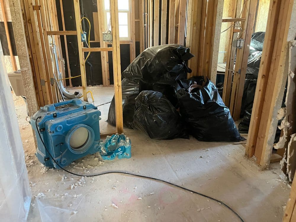 Renovation debris and equipment in a partially constructed room with black garbage bags.