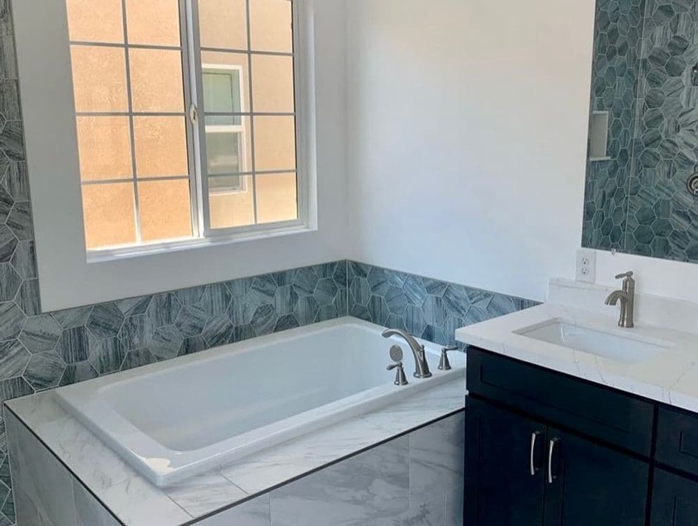 Modern bathroom featuring a white bathtub, stylish tile walls, and sleek fixtures.