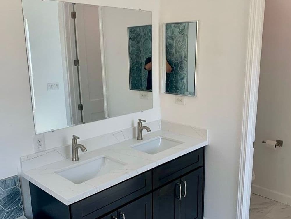 Modern bathroom with double sink vanity, marble countertop, and stylish mirrors.