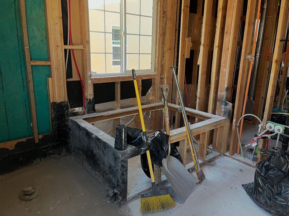 Construction site with framed window opening, cleaning tools, and construction materials.