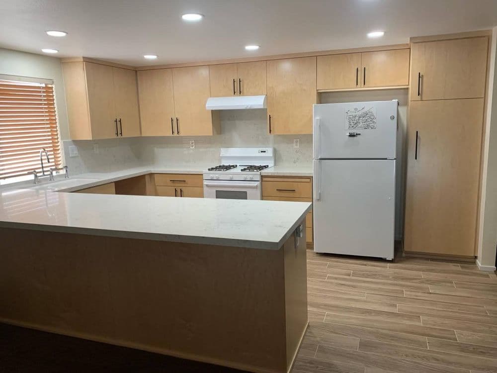 Modern kitchen with wooden cabinets, white appliances, and a central island. Bright and spacious layout.